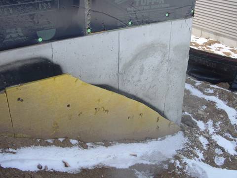 Exterior fiberglass insulation on this new home was (incorrectly) cut to terminate below-grade after backfill, which will expose the above-grade portions of the foundation wall to cold temperatures