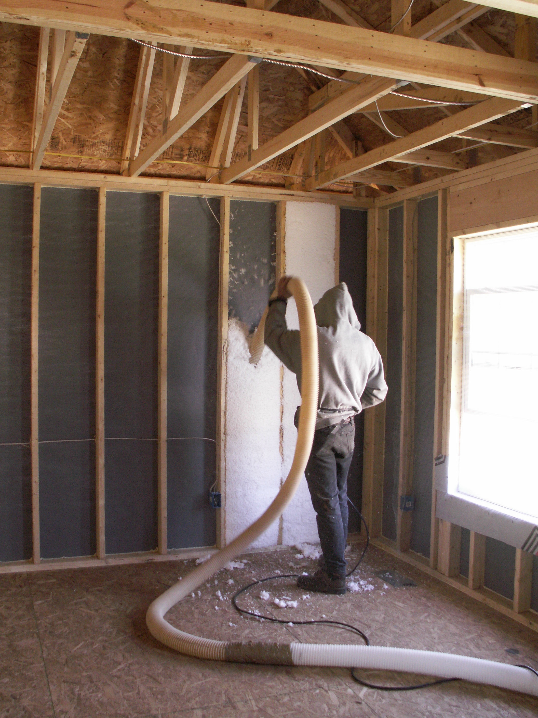 Blown fiberglass insulation fills netted wall cavities